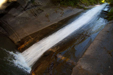 Sliding water over a rocky cliff in a lakeの写真素材