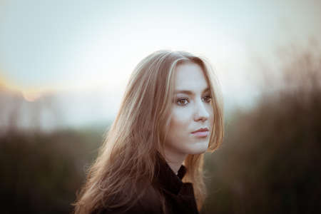 Young brunette girl in late autumn on sunset walking outdoorsの写真素材