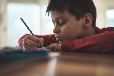 Boy writing homework reluctantly at homeの写真素材