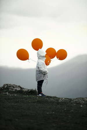 Small boy with balloons on top of mountainの写真素材