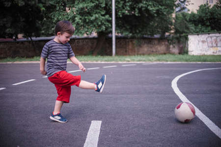 Smal boy kicking the ball in the schoolyardの写真素材