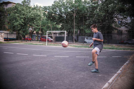 Yound boy kicking the ball in the playgroundの写真素材