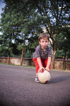 Small boy playing with a ball in the playgroundの写真素材