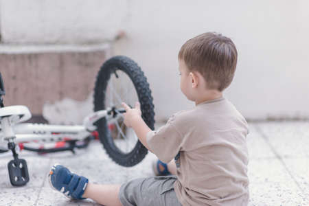 Toddler checking his bicycle tyreの写真素材