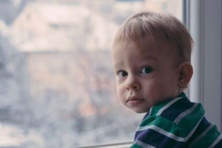 Small boy looking out the window to the snowの写真素材