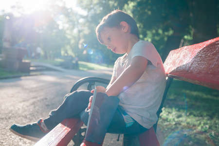 Kid eating popcorn in the bench in the park