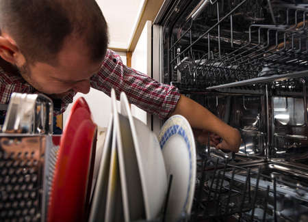 Handyman fixing the dishwasher in the kitchenの写真素材