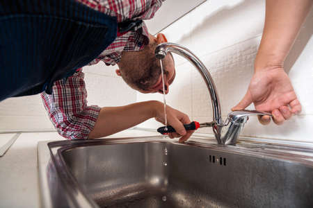 Handyman fixing the tap in the kitchen