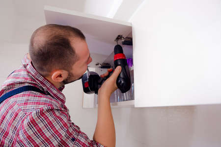 Handyman repairing the kitchen cabinet