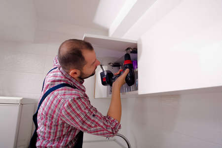 Handyman repairing the kitchen cabinet