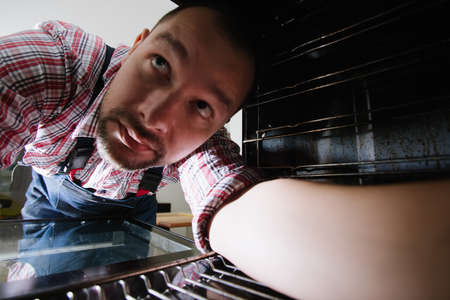 Handyman repairing the kitchen oven view from inside the oven