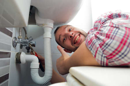 Handyman repairing the bathroom sink giving thumbs up