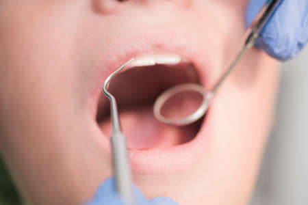 Boy with perfect teeth at the dentist doing check up with the clininc at the background - oral hygiene health care conceptの写真素材