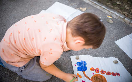 Creative child making artwork with brush and water colours on canvas near the parkの写真素材