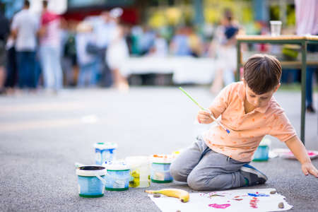 Toddler making atwork and painting with watercolors into the parkの写真素材