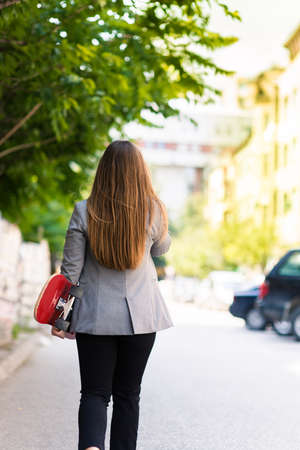 Photo from behind of a girl who holding skateboardの写真素材