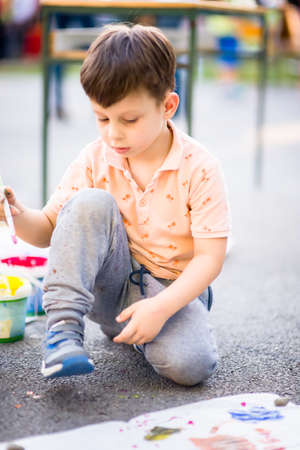 Beautiful kid holding painting brush and playing with colors near the city parkの写真素材
