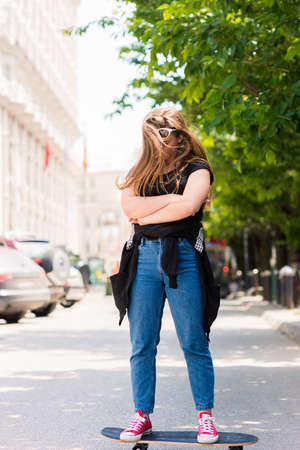 Cool teenage girl skater riding skateboard on the street. Outdoor.の写真素材