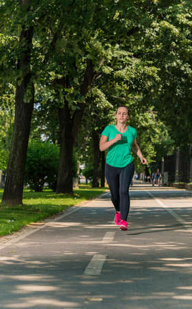 Young girl in a sports wear running through the parkの写真素材
