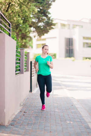 Full body portrait of an active young woman running outsideの写真素材
