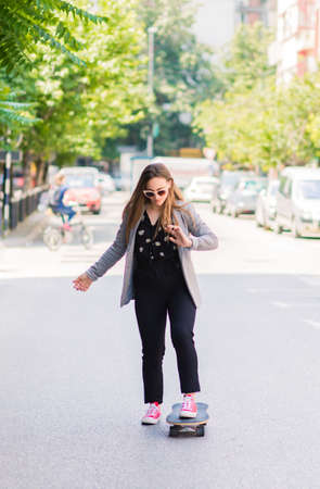 Attractive stylish young woman texting on her mobile phoneの写真素材