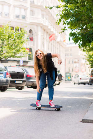 Portrait of cute teenage girl while driving skateboardの写真素材