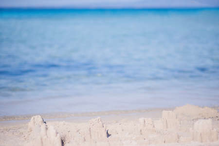 Castle made from sand standing near the clear sea water with no waves and clear blue skyの写真素材