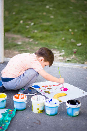 Cute kid near the park painting his picture with watercolors into the parkの写真素材