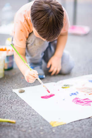 Boy who painting with watercolors  on his canvas on sunny day into the parkの写真素材