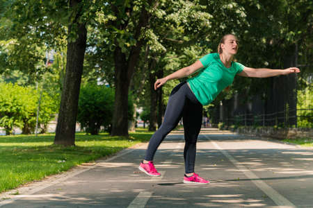 Full body portrait of an active young woman stretching in a parkの写真素材