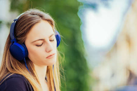Young beautiful girl enjoying in the music who listening in the parkの写真素材