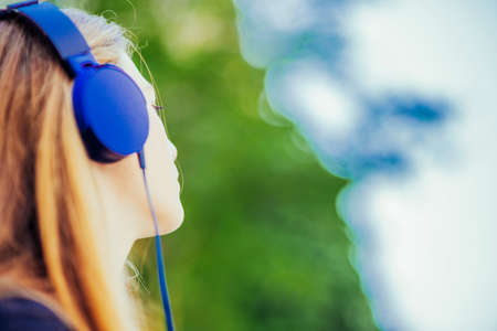 Beautiful woman listening to music through headphones in the parkの写真素材