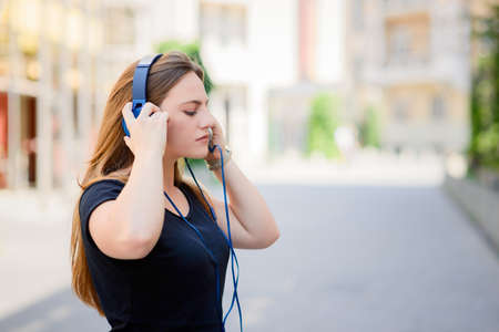 Girl listening to music streaming with headphones in summerの写真素材