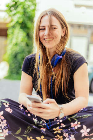 Teenager girl with blue headphone smilling while sitting on the benchの写真素材