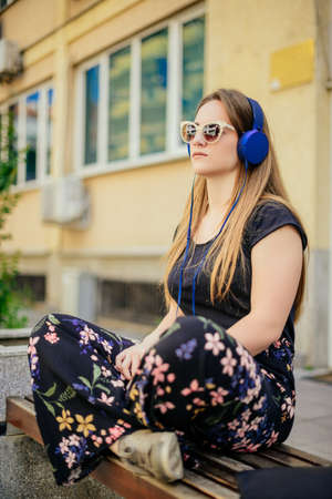 Beautiful woman listening to music through headphones in the parkの写真素材