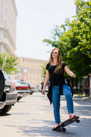Portrait of cute teenage girl while driving skateboard down the street parkingの写真素材