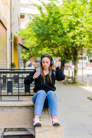 Shot of young woman listening to music with mobile phone outdoorの写真素材