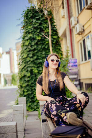 Young and beautiful girl posing while listening music on sunny dayの写真素材