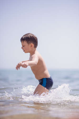 Cute boy in the shallow water runningの写真素材