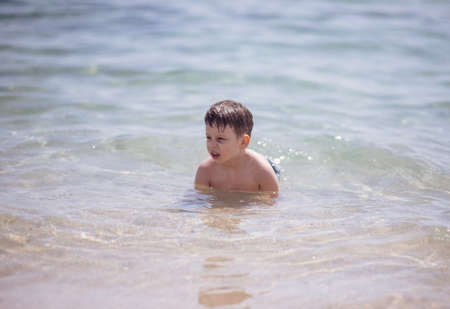 Cute boy in the shallow water looking at the cameraの写真素材