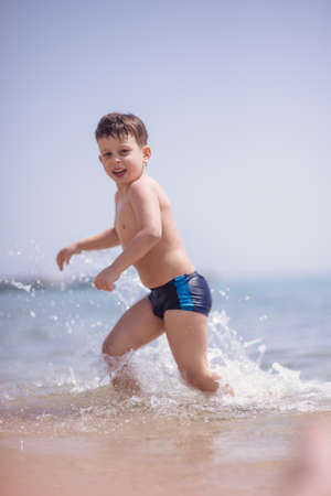 Cute boy in the shallow water runningの写真素材