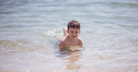 Cute boy in the shallow water looking at the cameraの写真素材