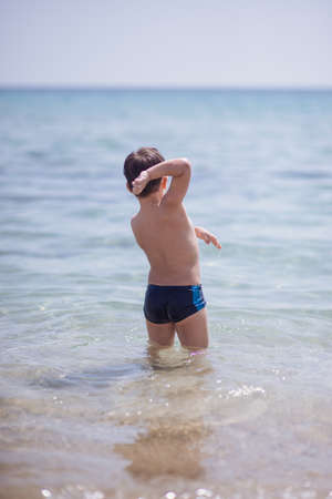 Cute boy in the shallow water looking at the cameraの写真素材