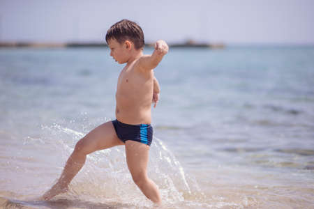 Cute boy in the shallow water runningの写真素材