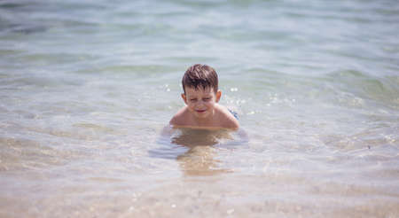 Cute boy in the shallow water looking at the cameraの写真素材