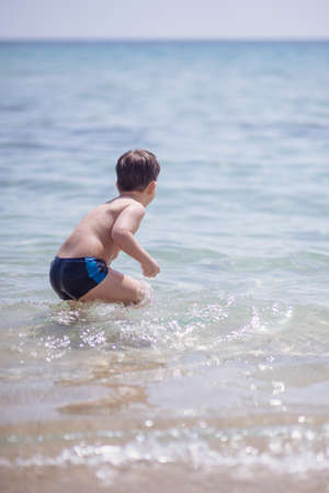Cute boy in the shallow water looking at the cameraの写真素材