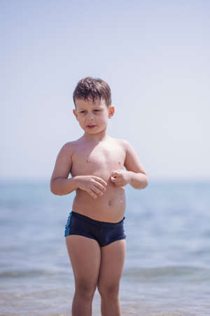 Cute boy in the shallow water looking at the cameraの写真素材