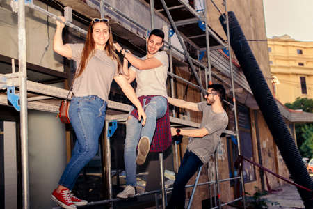 Three friends enjoying on construction building while standing on scaffolding