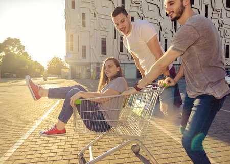 Photo of two guys pushing a girl in a shopping trolleyの写真素材