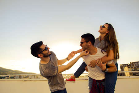 Three group of friends enjoying in the view on the city from rooftopの写真素材